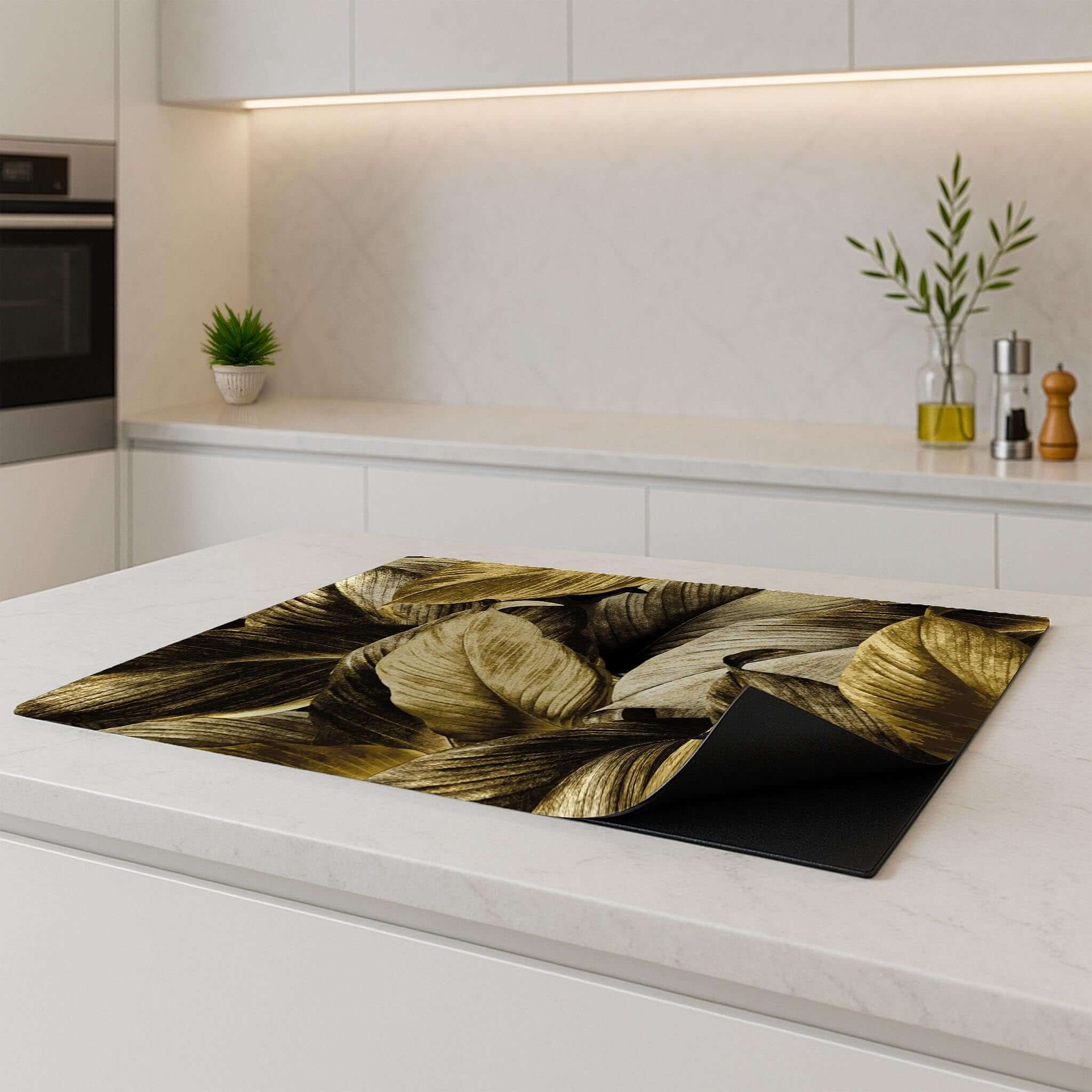 Golden Leaves inductie beschermer – luxe bladmotief met gouden tinten, opgerolde hoek op modern keukenblad