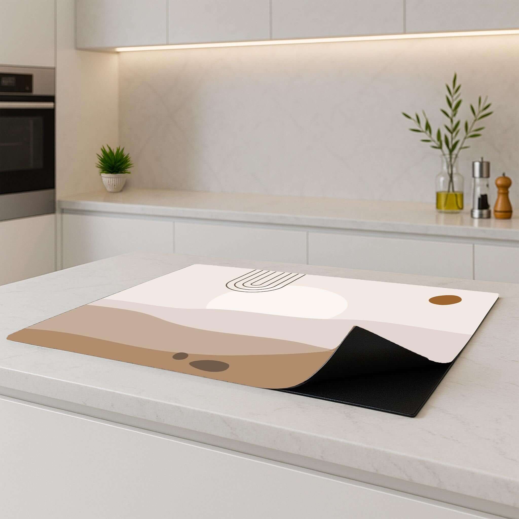 Desert Glow Inductie Beschermer on a kitchen counter, featuring soft desert colors and organic shapes for a minimalistic look.