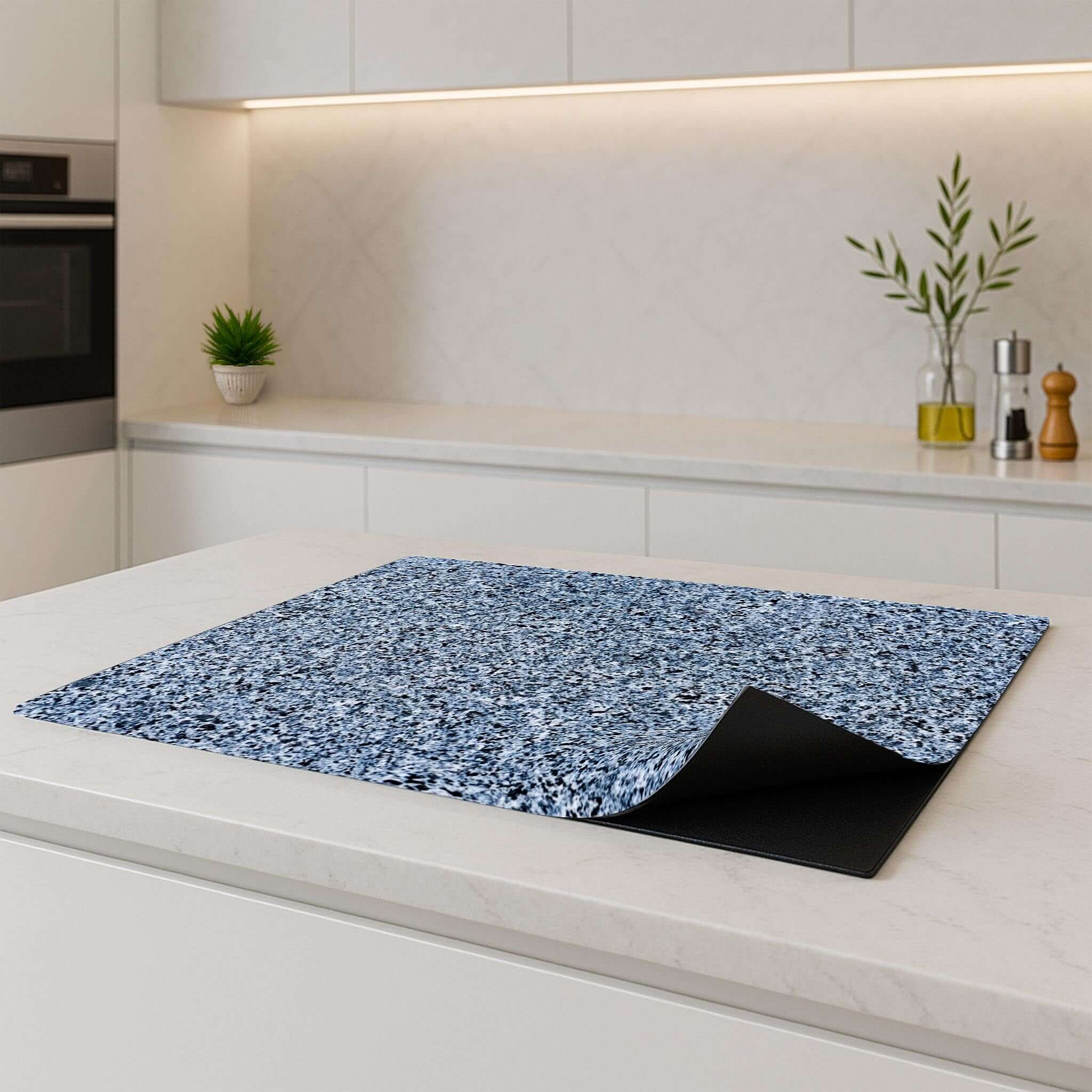 Baltic Granite inductiebeschermer liggend op een modern wit keukenblad met opgerolde hoek