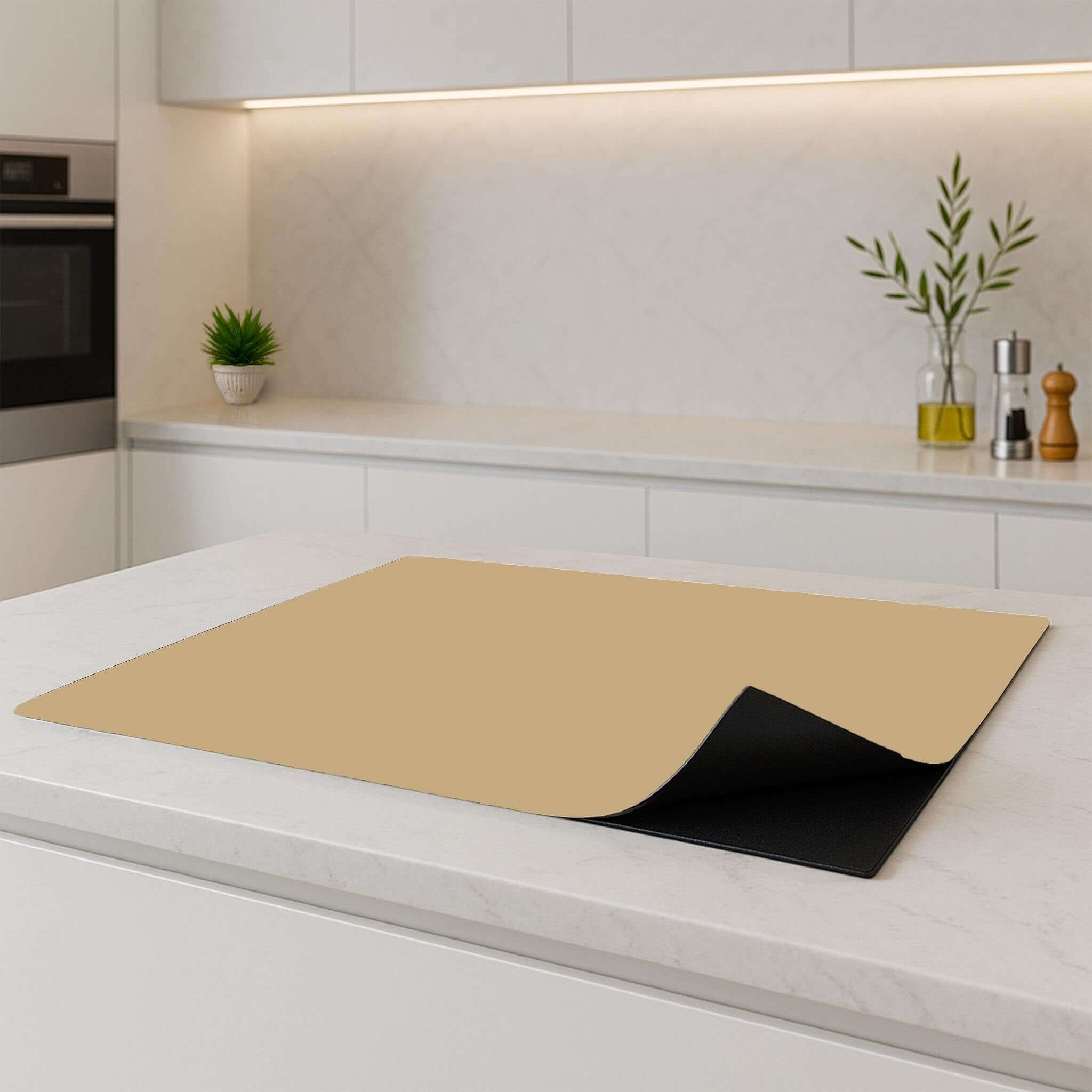 Champagnekleurige inductiebeschermer als extra werkruimte in een moderne keuken.