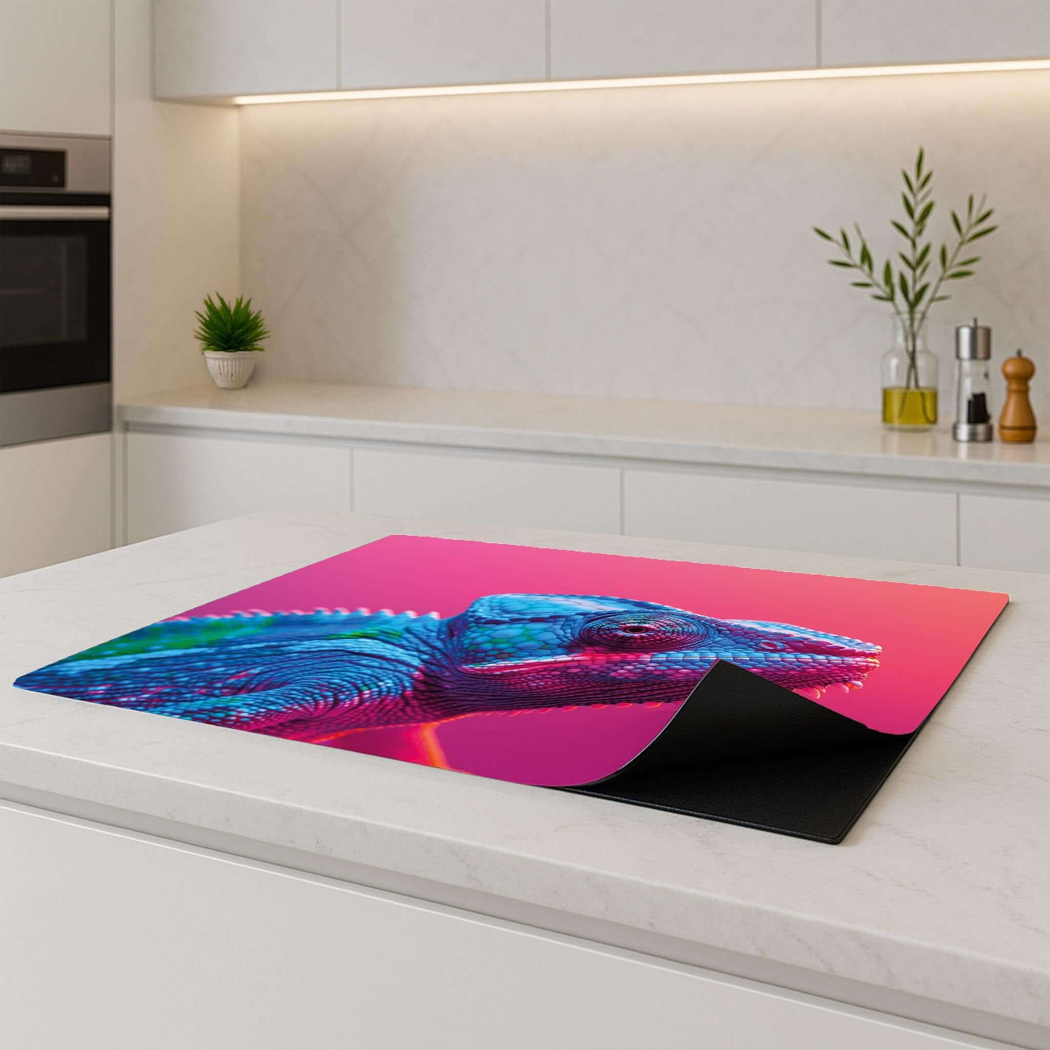 Inductiebeschermer met kleurrijke kameleon op roze, geplaatst op modern keukenblad