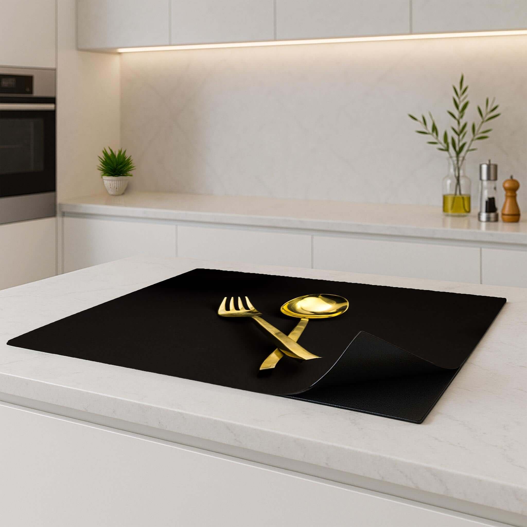 Dining Deluxe Inductie Beschermer on a kitchen countertop with gold cutlery accents.