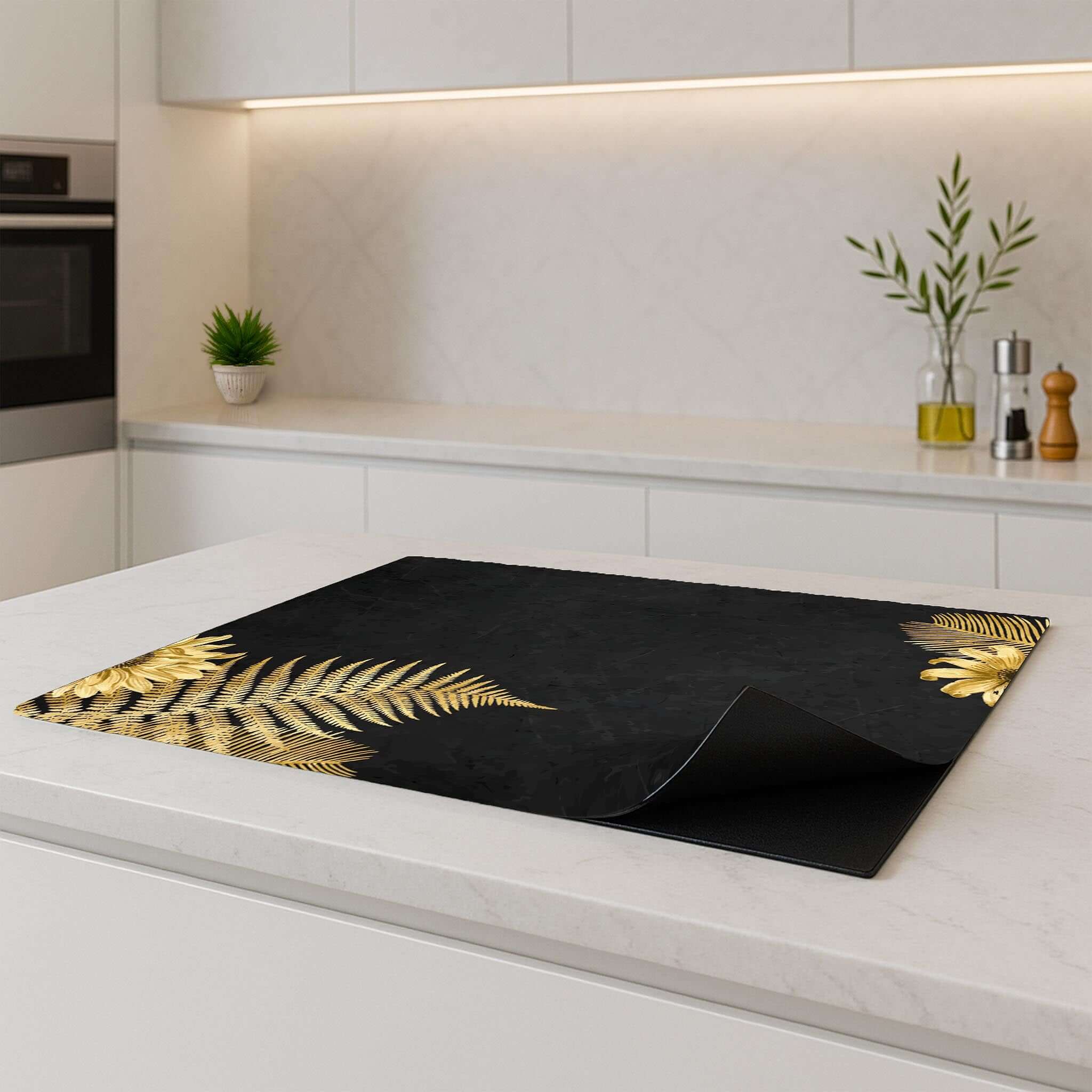 Golden Fern Touch inductiebeschermer op een modern wit keukenblad, met gouden varens als eyecatcher.