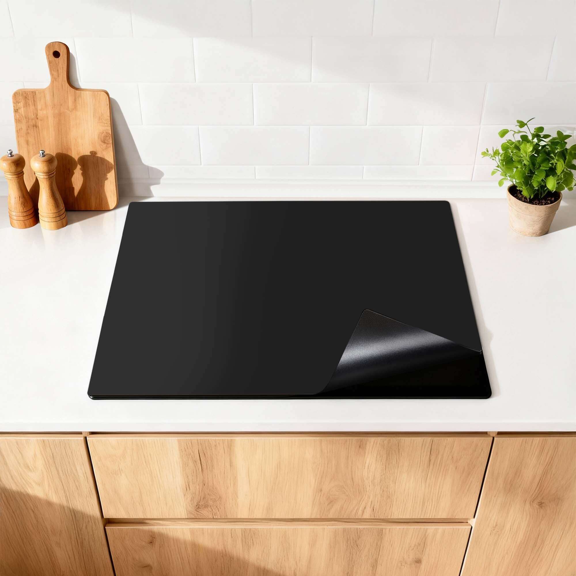 Pure Black – Inductie Beschermer op een moderne keukentafel, minimalistisch design.