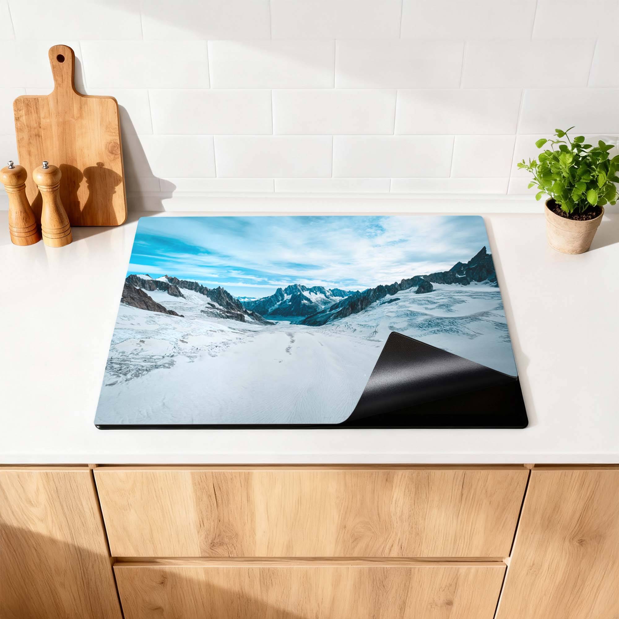 Frozen Peaks – Inductie Beschermer op een keukenblad met besneeuwde bergen.