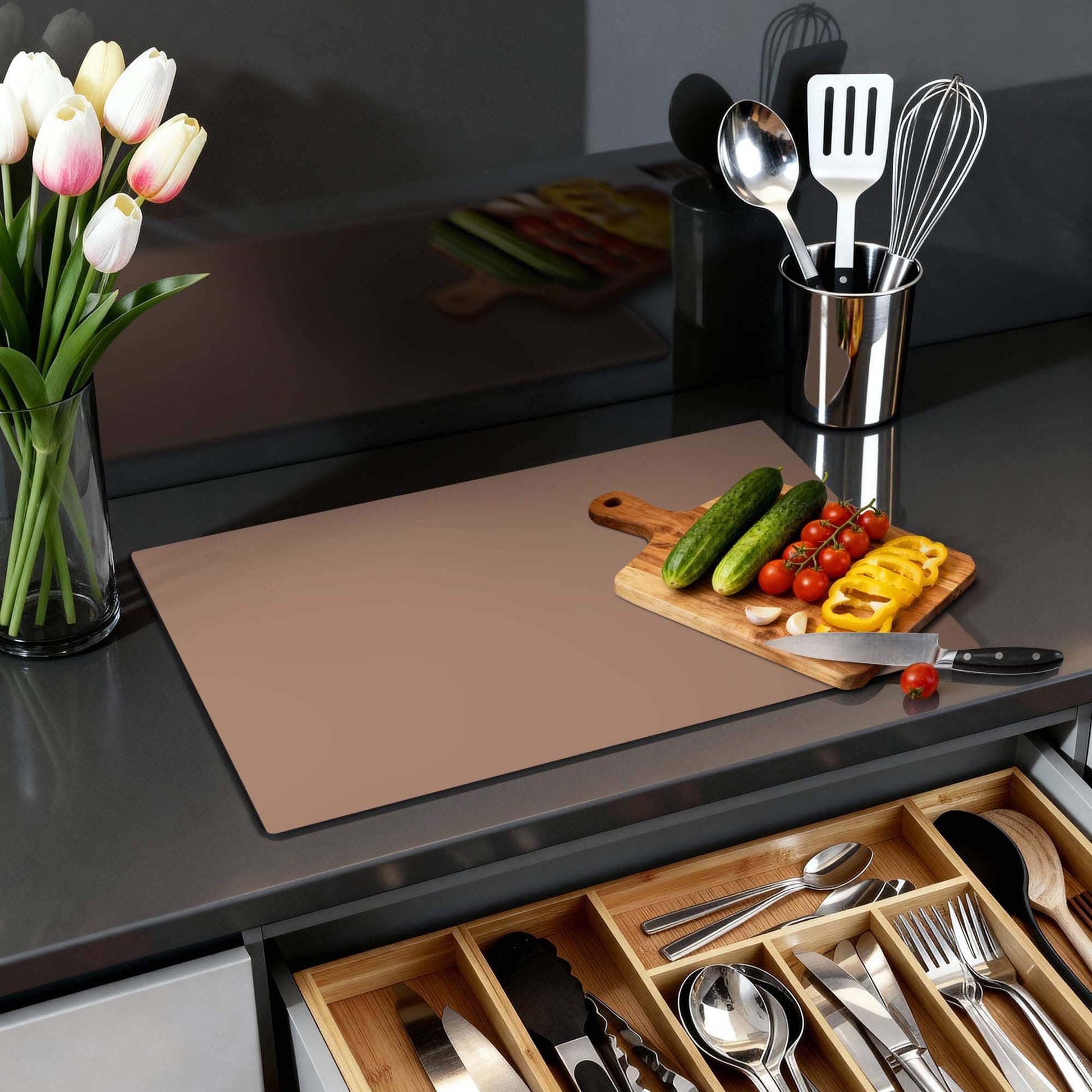 Mocha Mousse – Inductie Beschermer op een keukenblad met groenten en een vaas bloemen.