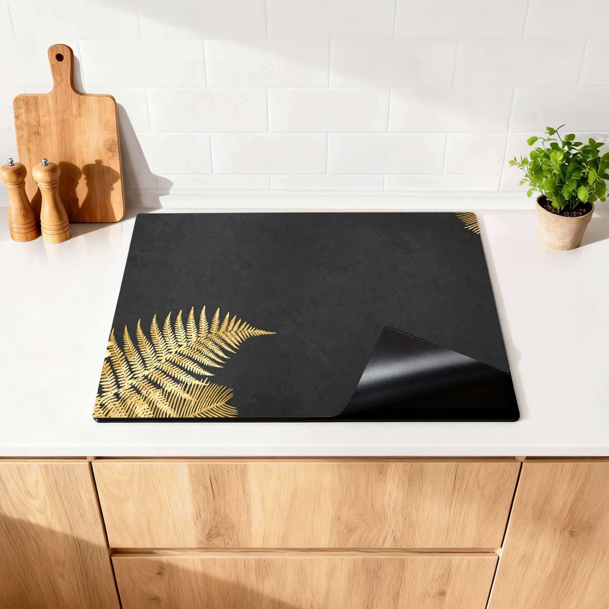 Golden Fern Touch – Inductie Beschermer met gouden varens op zwarte achtergrond in keuken.