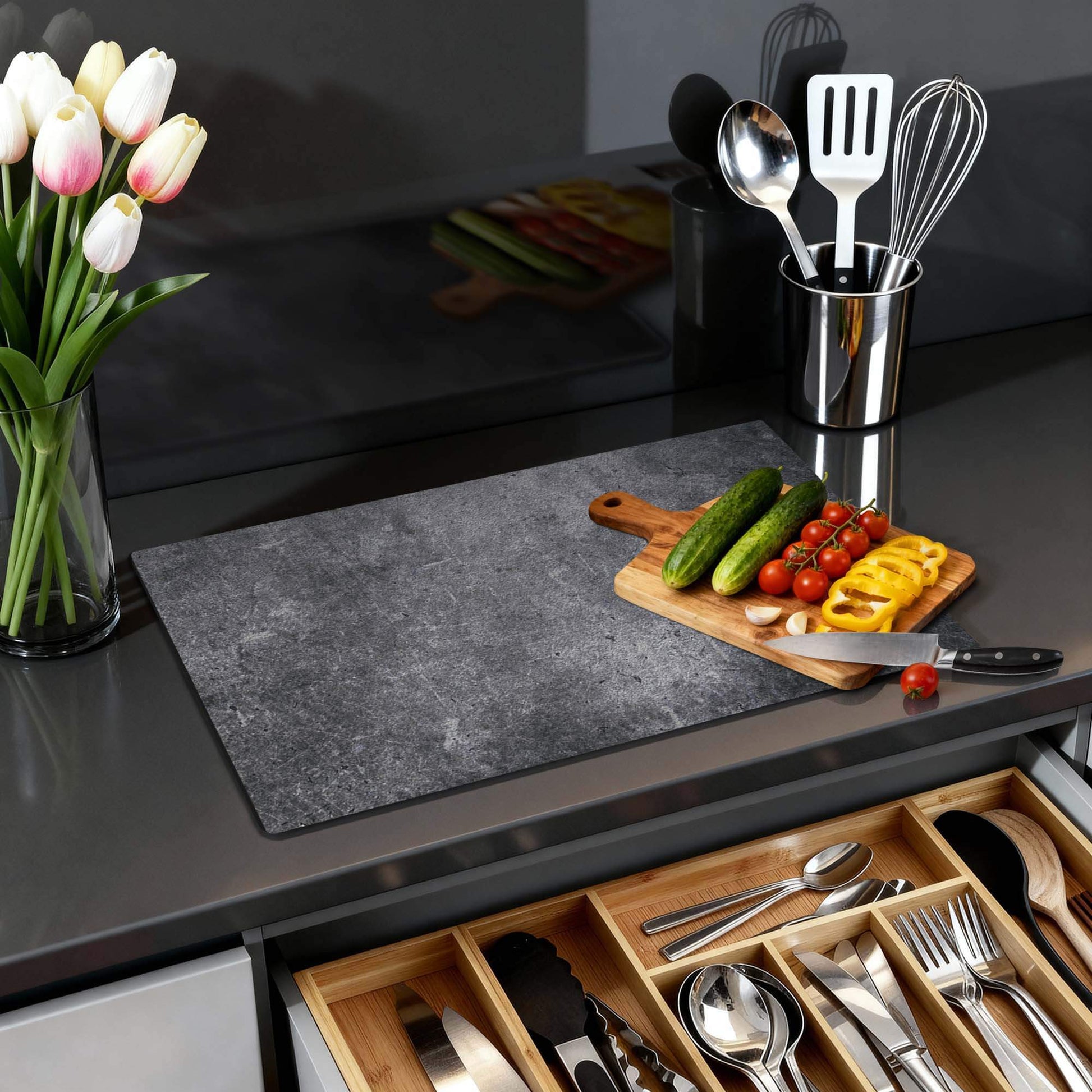 Midnight Concrete – Inductie Beschermer op een moderne keukenwerkblad met groenten en keukengerei.