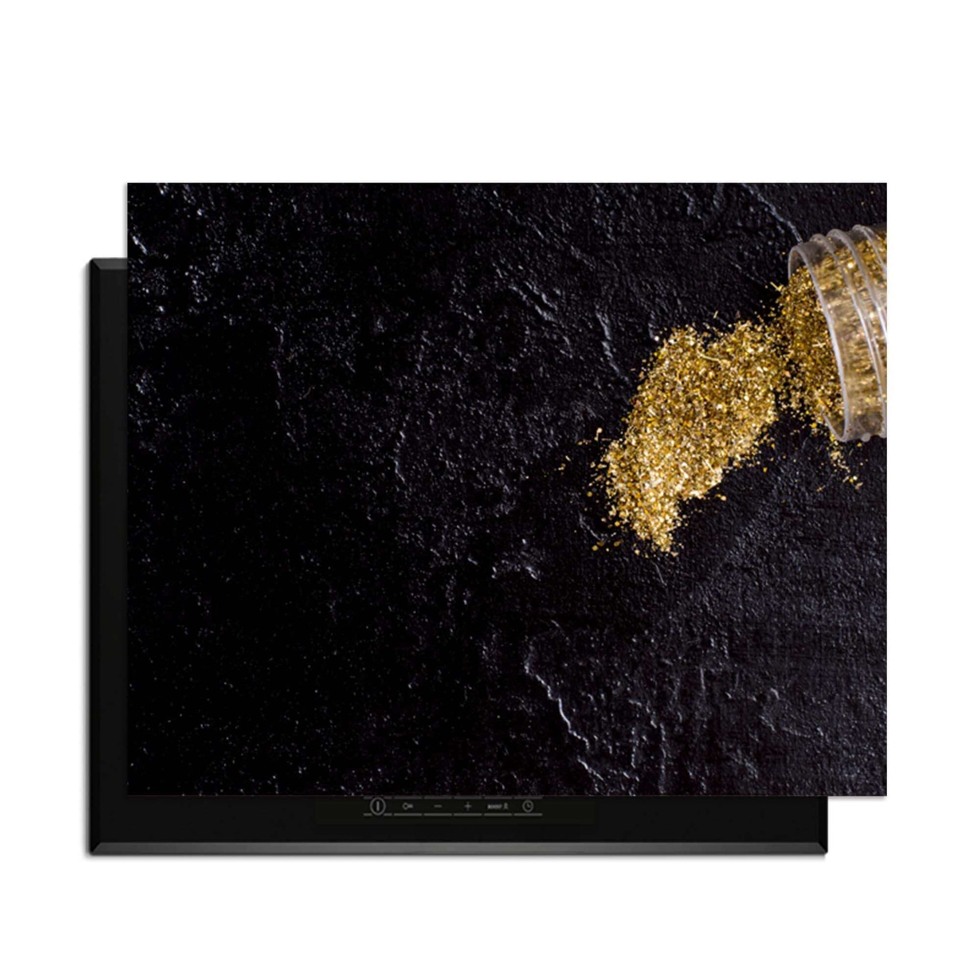 Spilled Gold - Inductie Beschermer op een zwarte achtergrond met goudkleurig poeder.