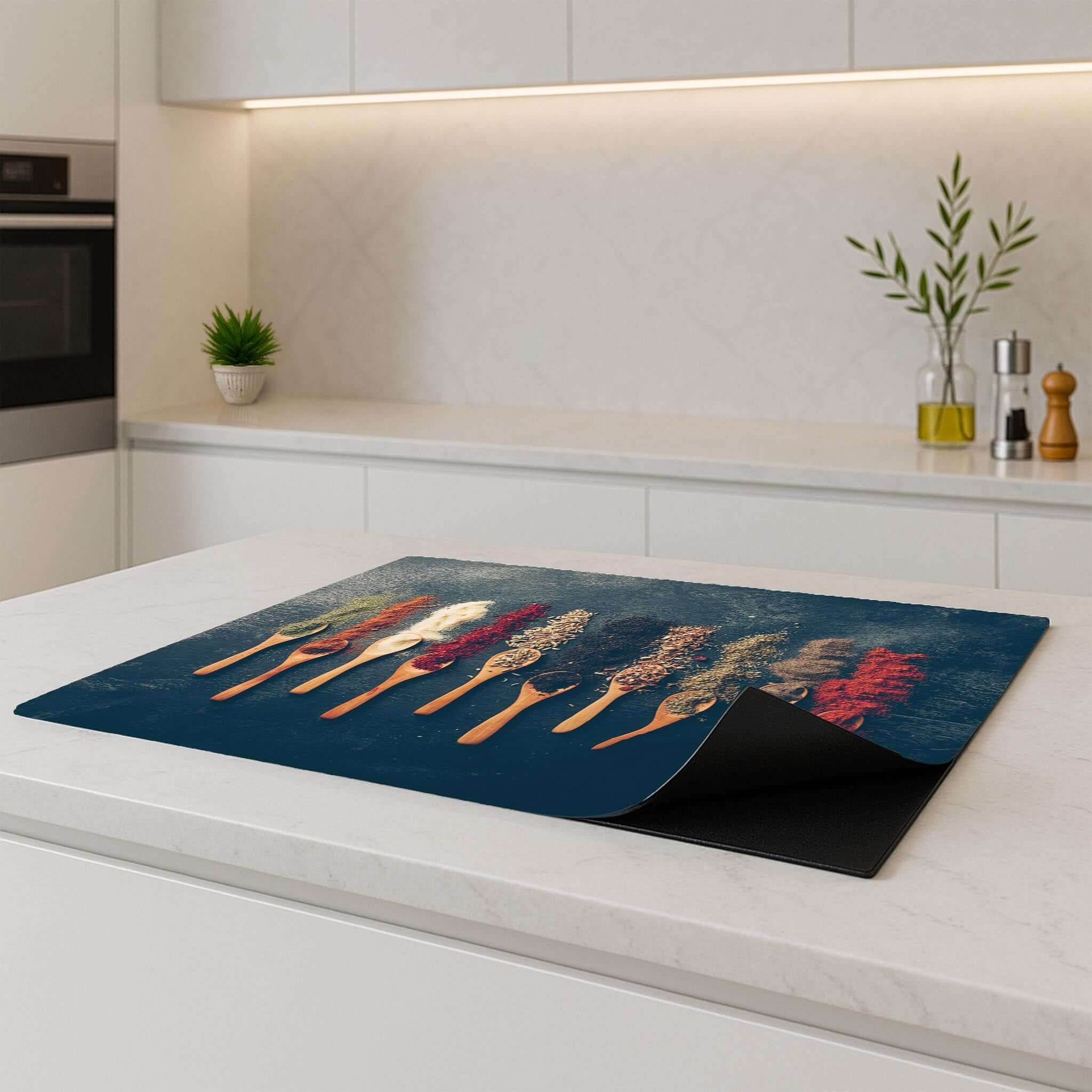 De Spice Palette inductiebeschermer met kruidenontwerp op een inductiekookplaat in een moderne keuken.