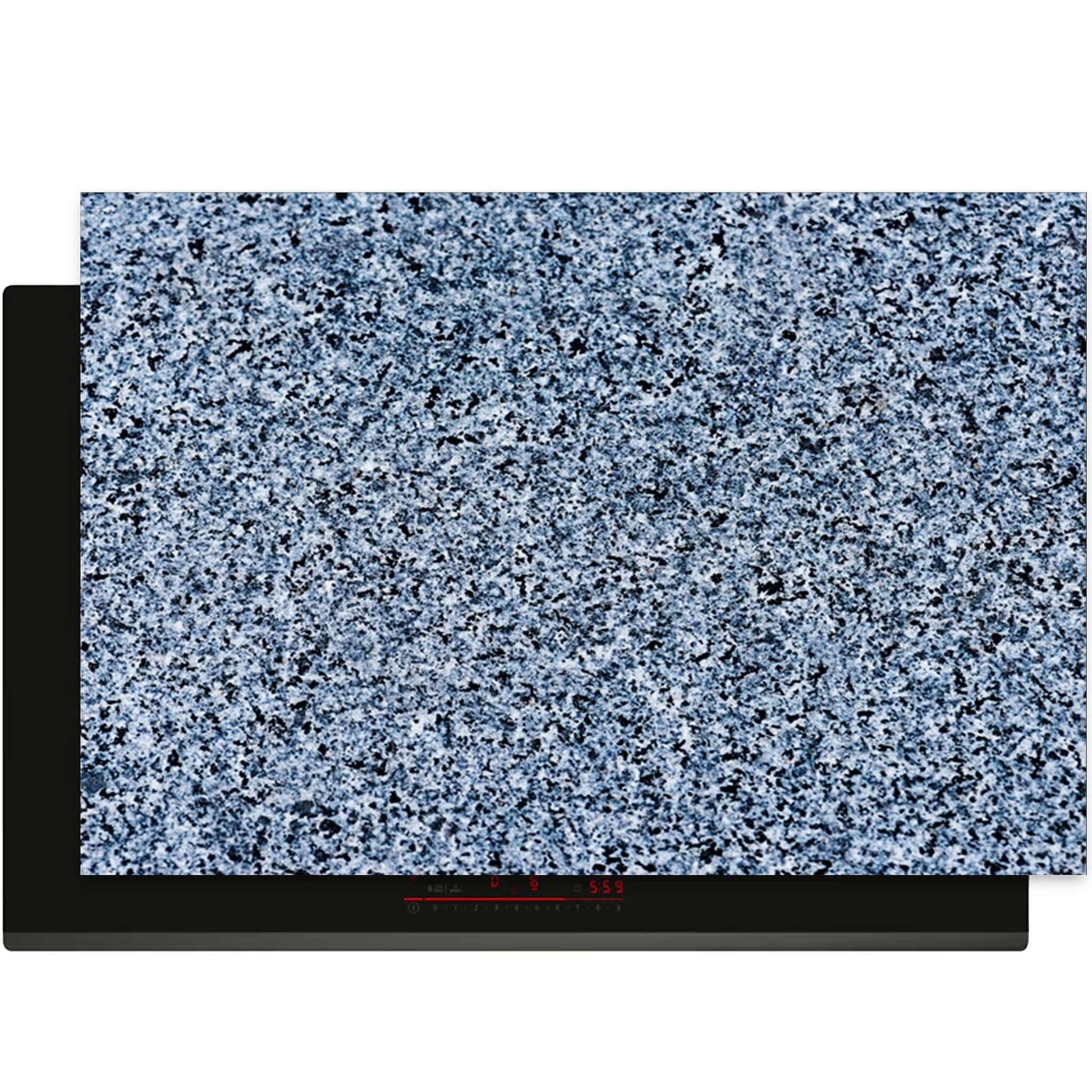 Baltic Granite inductiebeschermer op een zwarte inductiekookplaat met realistisch granietpatroon