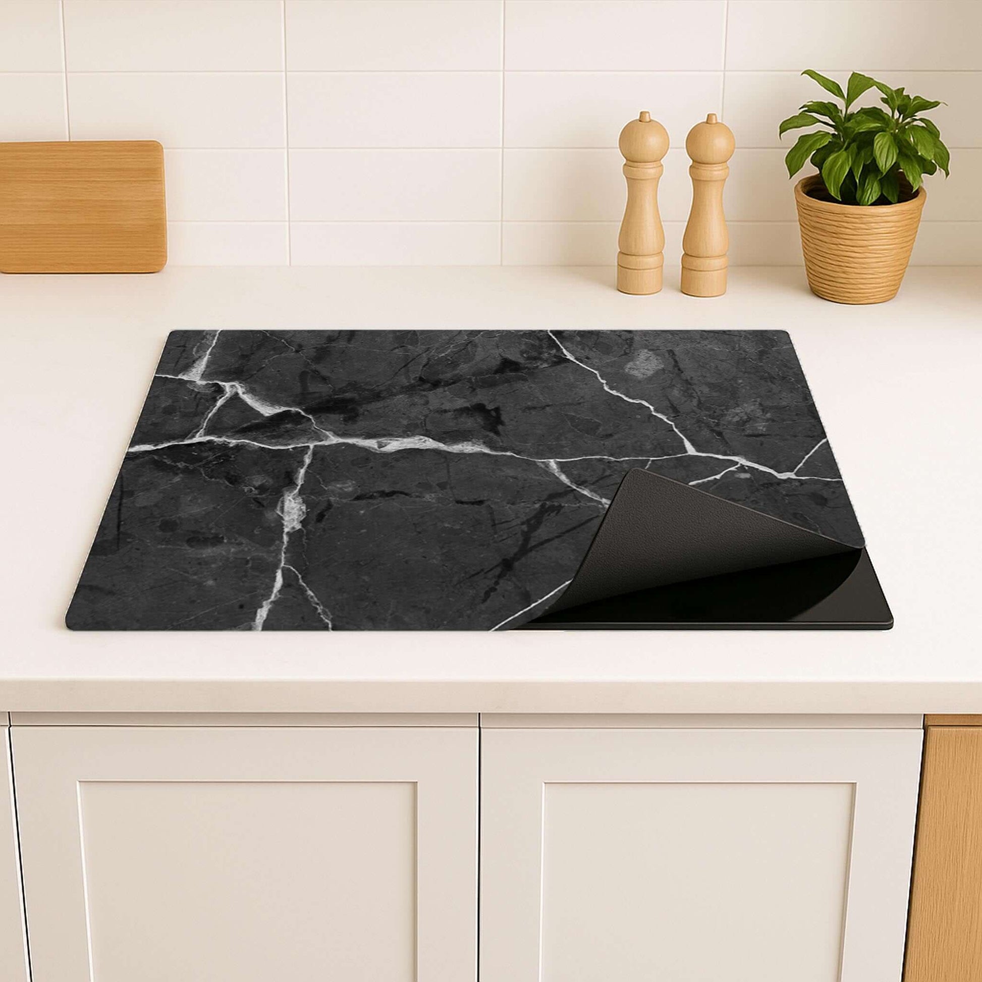 Detailfoto van de Black Marble inductie beschermer op een inductiekookplaat in een lichte keuken