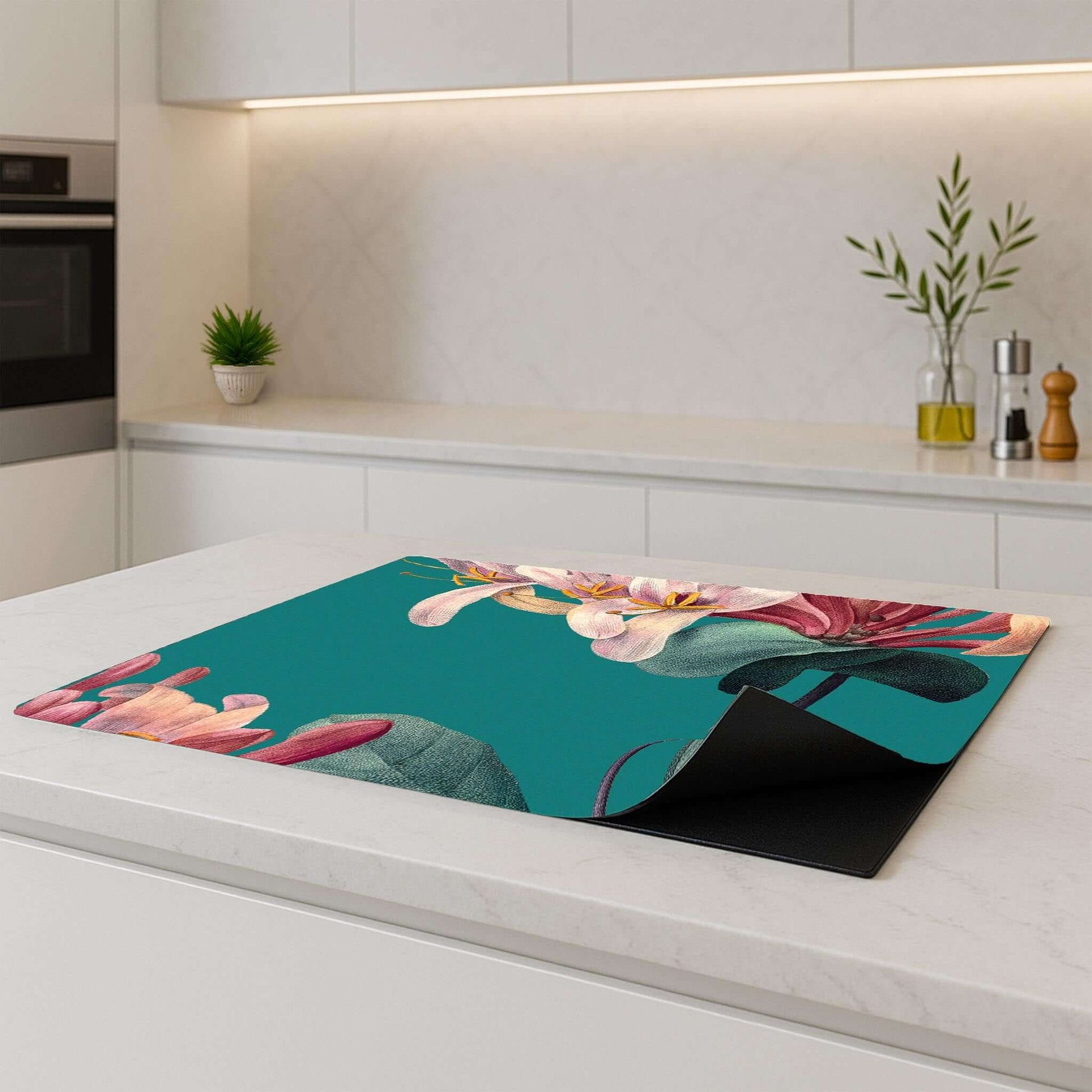 Vintage bloemen inductiebeschermer liggend op een inductiekookplaat in een moderne keuken