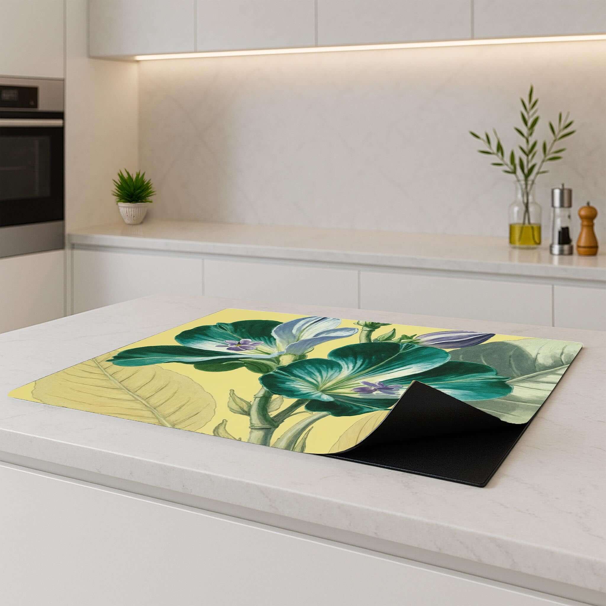 Gele inductiebeschermer met botanisch design op wit keukeneiland