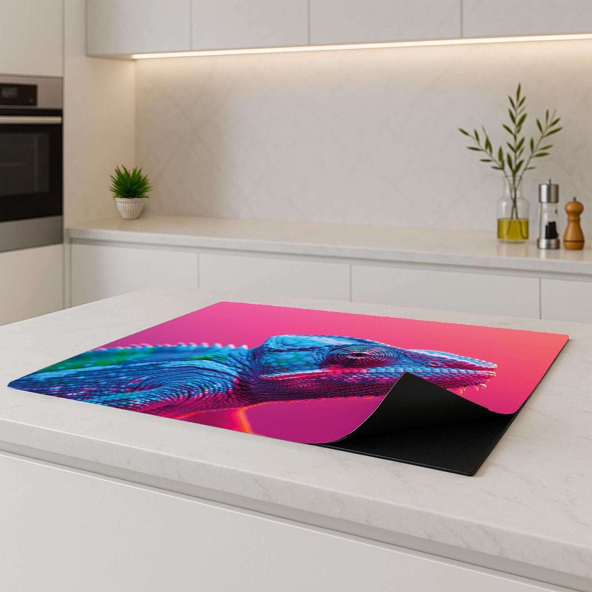 Inductiebeschermer met kleurrijke kameleon op roze, geplaatst op modern keukenblad
