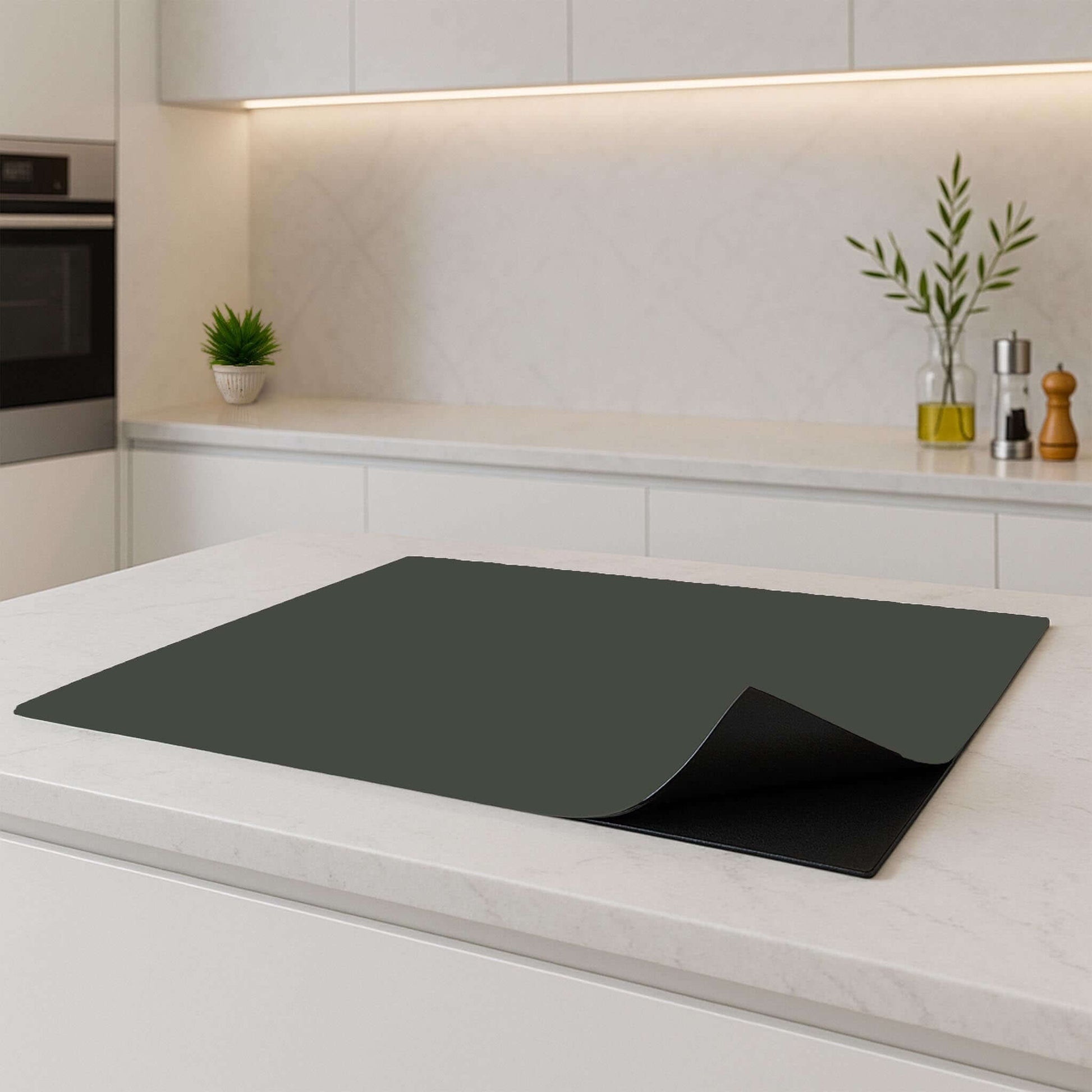 Mosgroene inductiebeschermer op wit aanrecht in moderne keuken