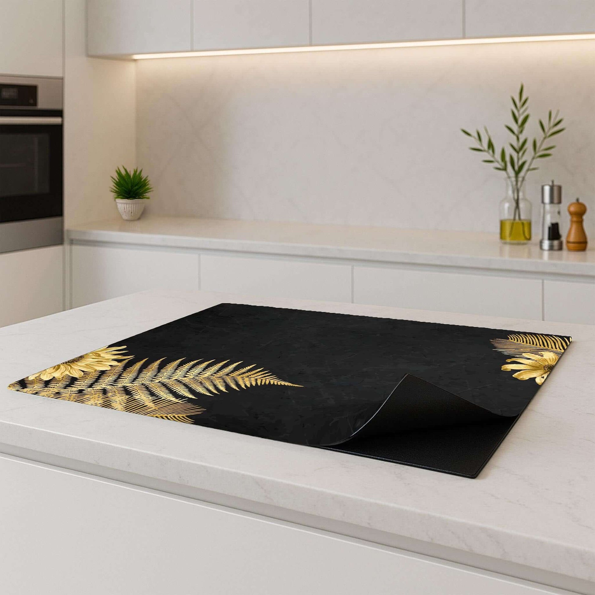 Golden Fern Touch inductiebeschermer op een modern wit keukenblad, met gouden varens als eyecatcher.