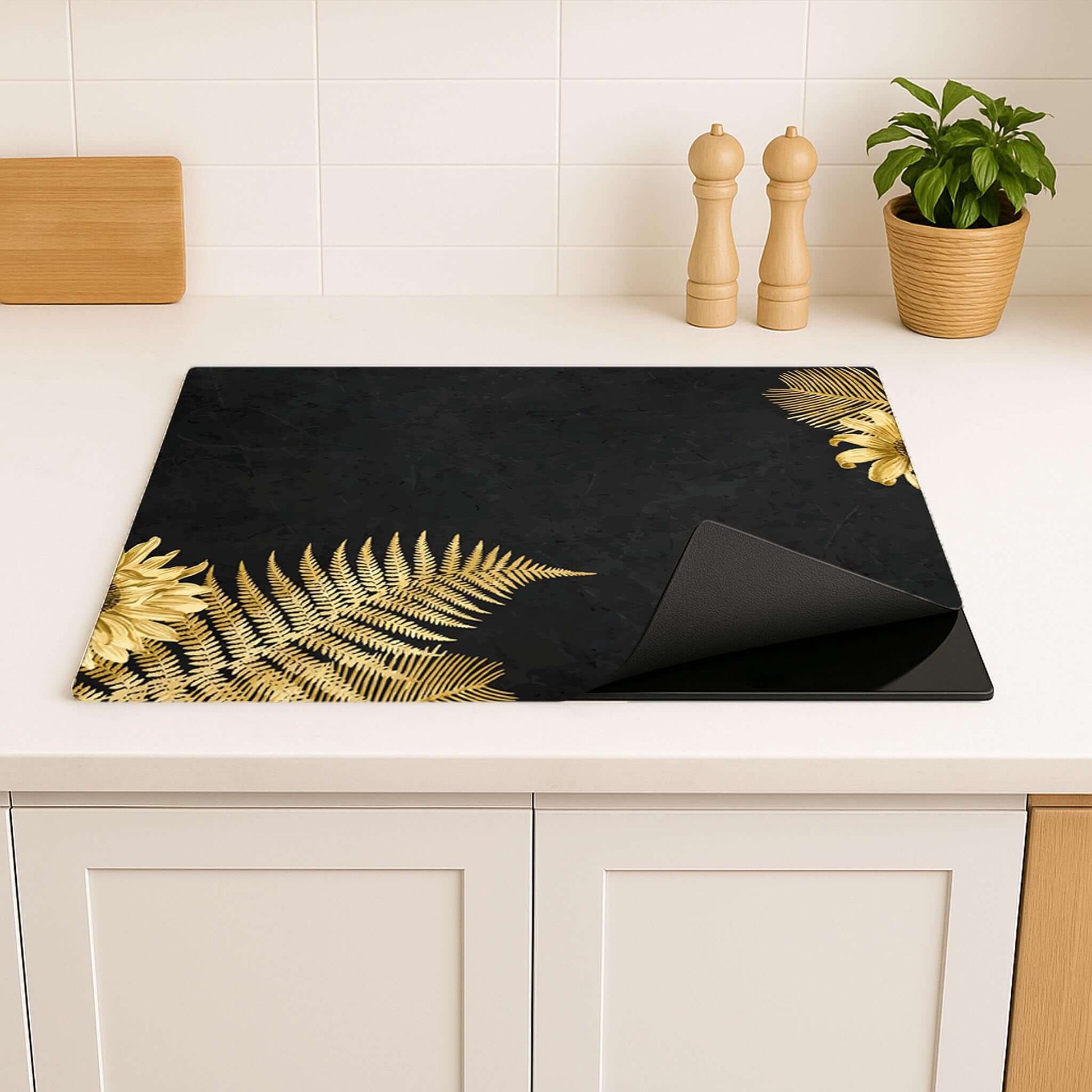 Inductiebeschermer met gouden bladeren, stijlvolle blikvanger in een lichte, moderne keuken.