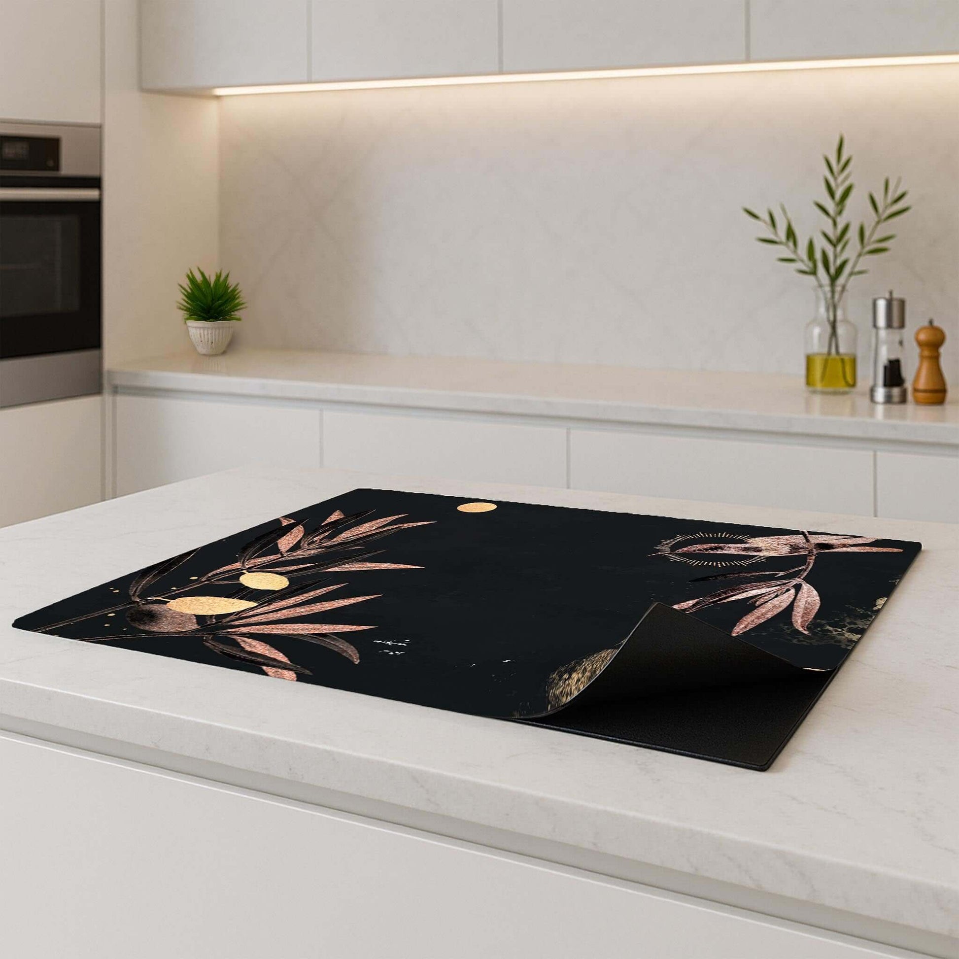 Luxe inductie beschermer met gouden olijftakken, stijlvol geplaatst op een kookplaat in een lichte keuken