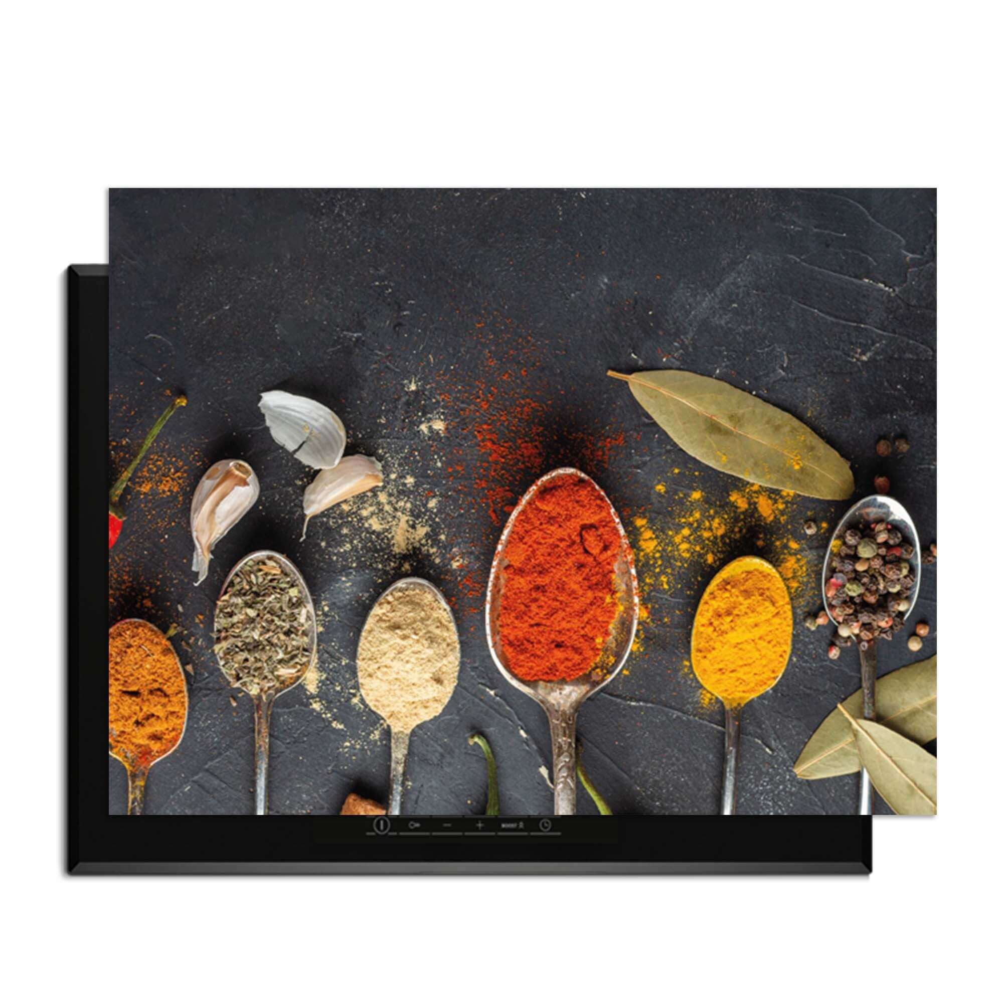 Spice Essence - Induction Protector mit Löffeln voller aromatischer Gewürze auf dunklem Hintergrund.