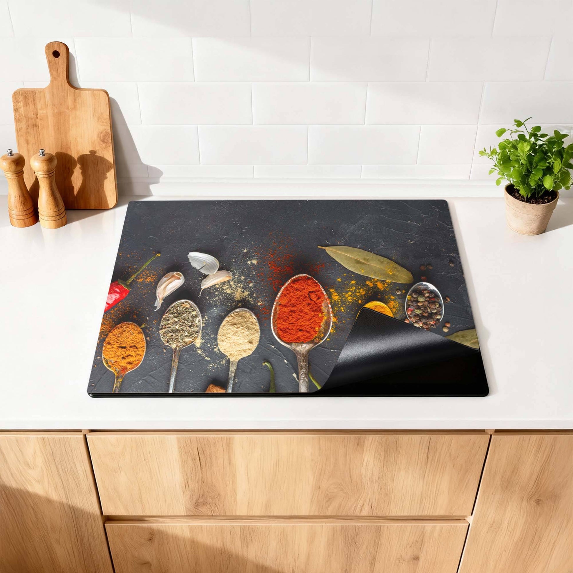 Spice Essence - Induction Protector mit Löffeln voller Gewürze auf einem dunklen Hintergrund in der Küche.