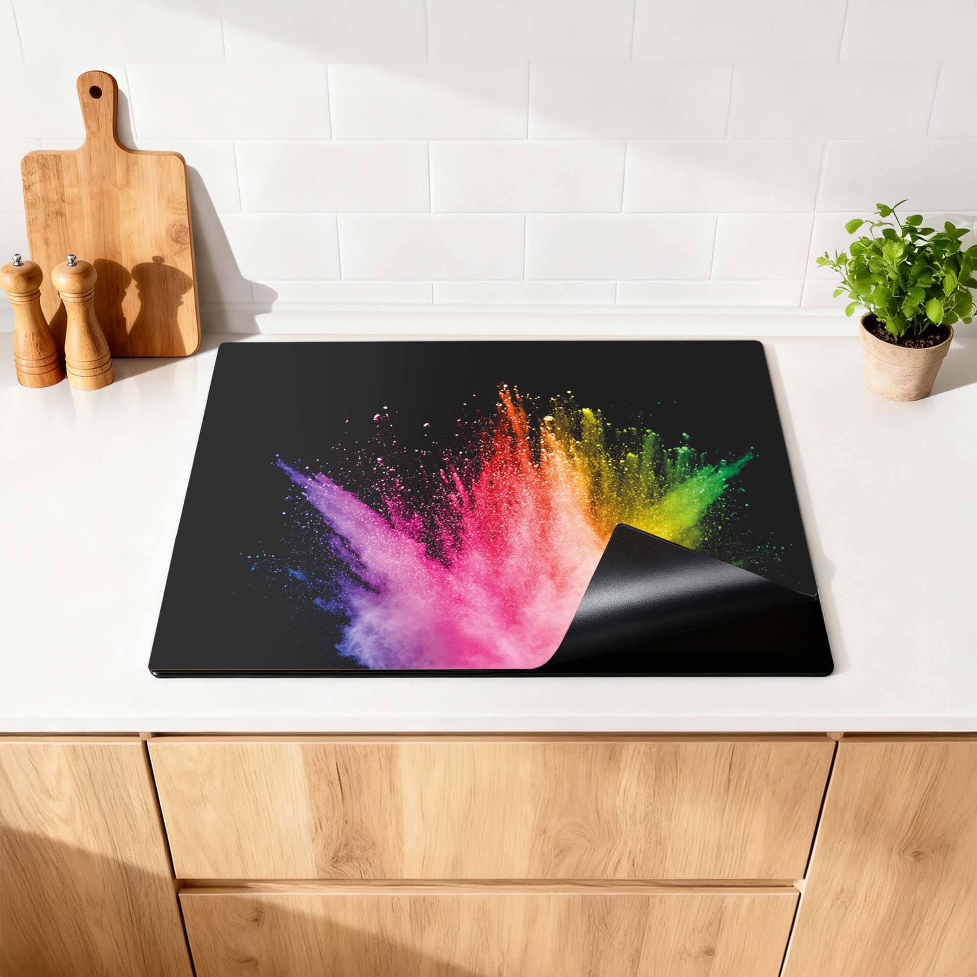 Prism Pulse – Inductie Beschermer met kleurrijke spetters op een zwarte achtergrond op een keukenblad.