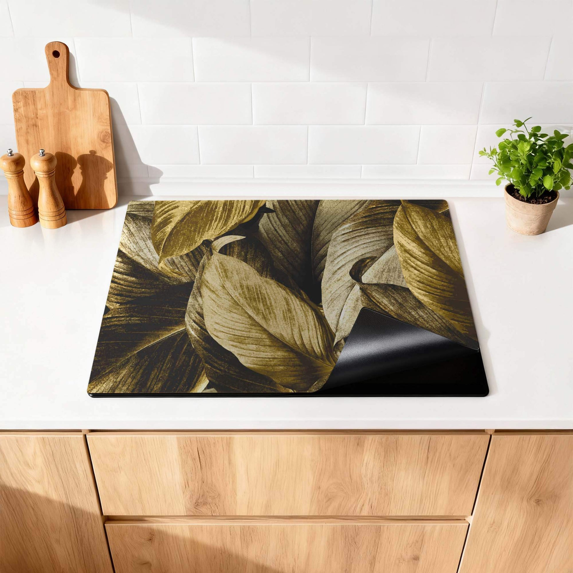 Golden Leaves – Inductie Beschermer met botanische luxe op een keukenblad.