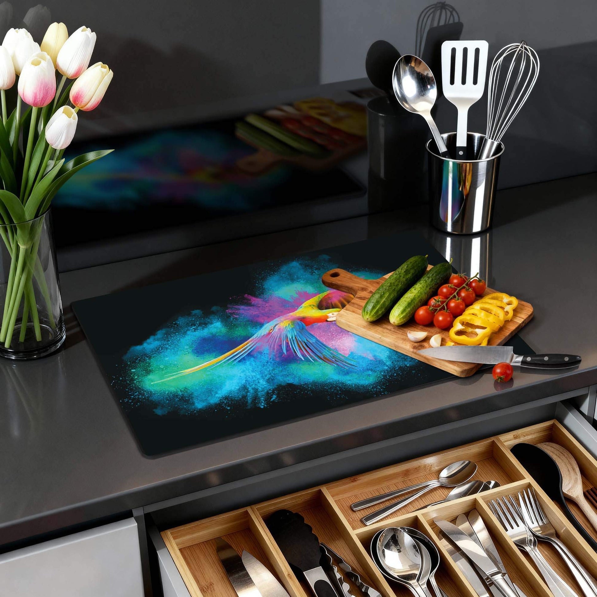 Color Flight – Inductie Beschermer met kleurrijke papegaai op keukenblad met groenten.