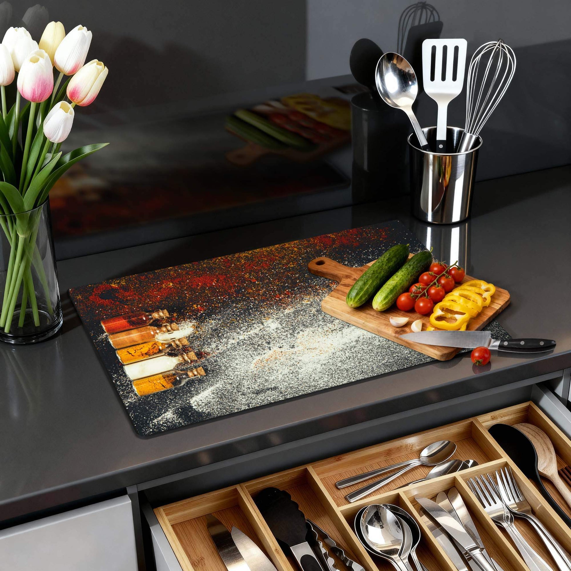 Kleurrijke Spice Bottles – Inductie Beschermer op een moderne keukentafel met verse ingrediënten en tulpen.