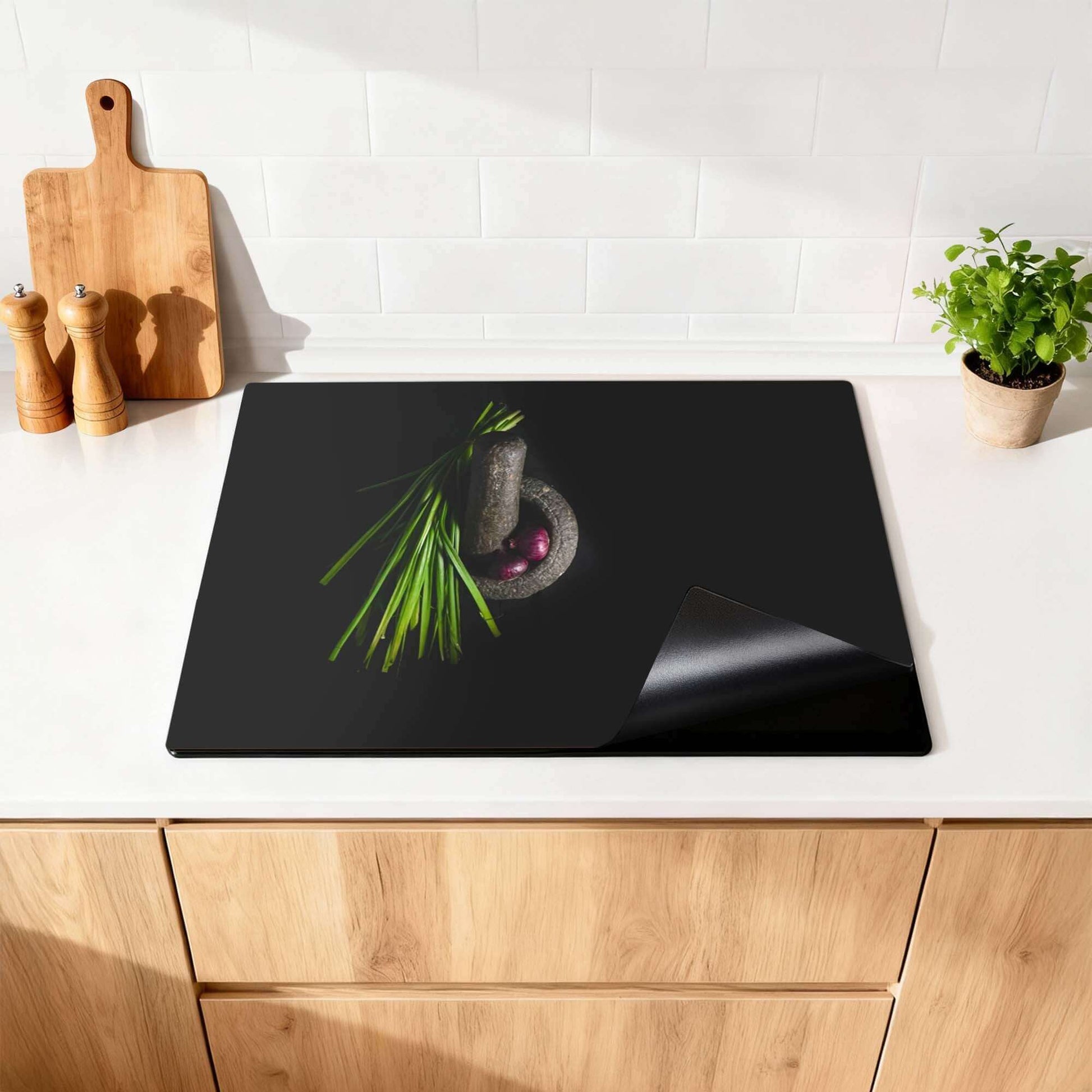 Midnight Herb - Inductie Beschermer op een keukenblad met kruiden en een vijzel.