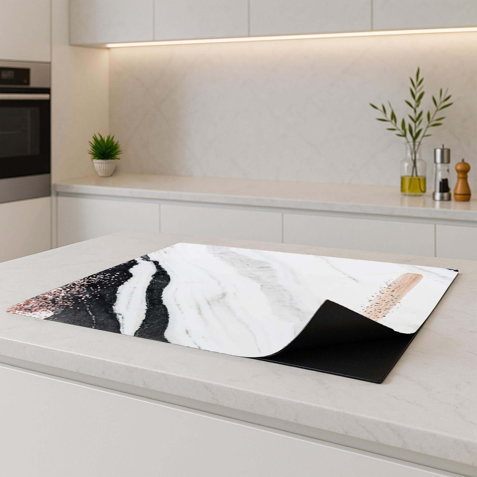 Marble Blush Inductie Beschermer op een kookplaat in een moderne keuken, met blush en brons details