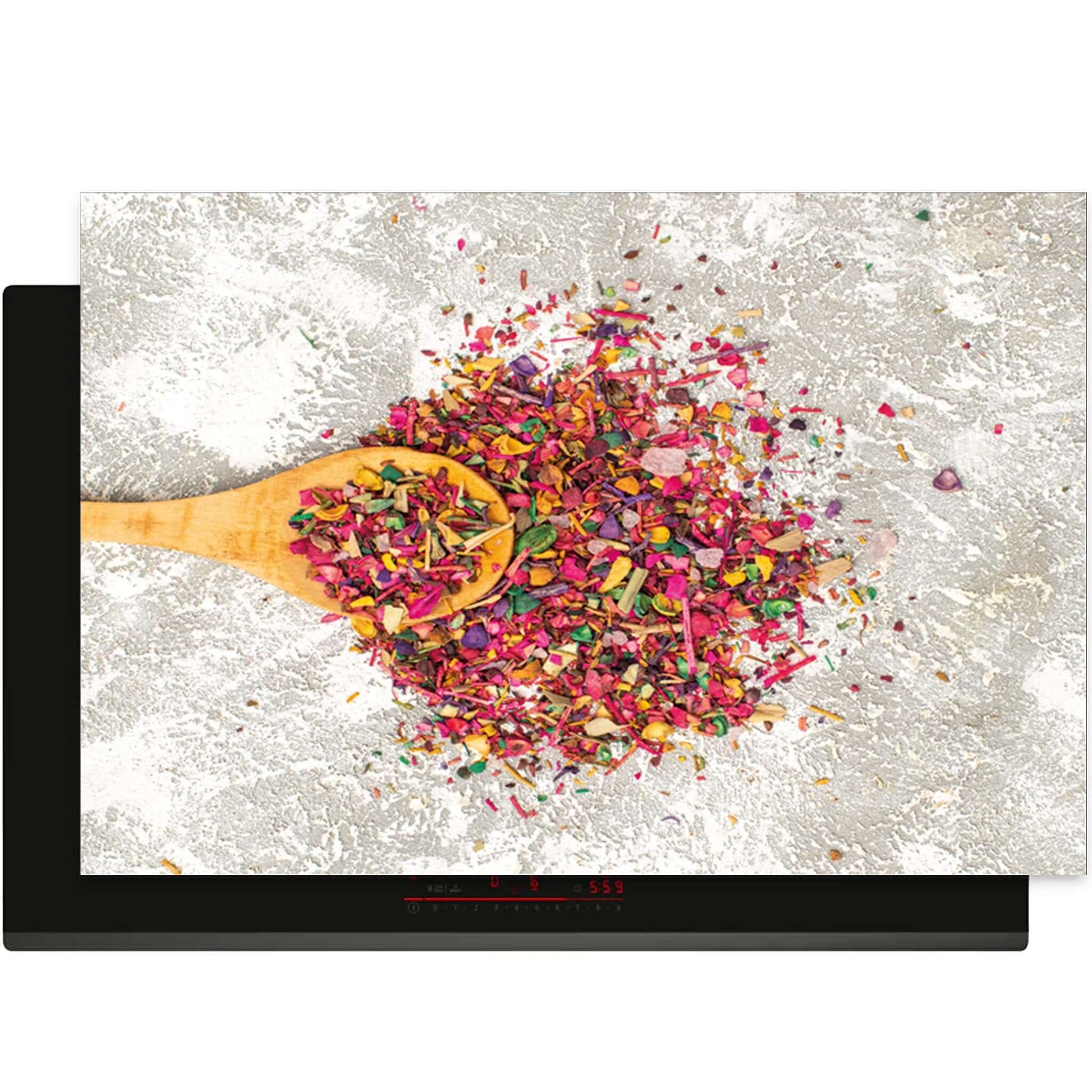Bovenaanzicht van de Spice Delight inductiebeschermer met kleurrijke kruiden en houten lepel
